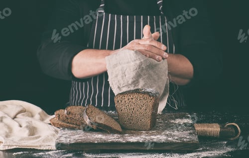 Preview: Chef In Black Uniform Sliced Baked Rye Bread On A Brown Wooden Board Sprinkled With White Flour And