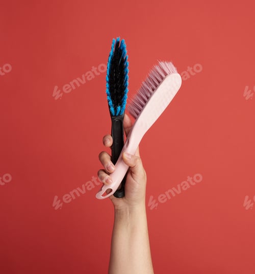 Preview: Female Hand Holds Black Plastic Cleaning Brush, Red Background, Close Up