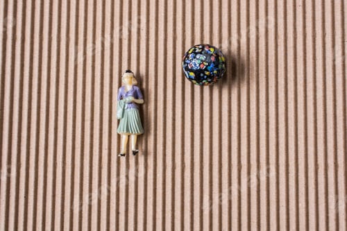 Preview: Little Woman Figurine On Paper Beside A Colorful Marble