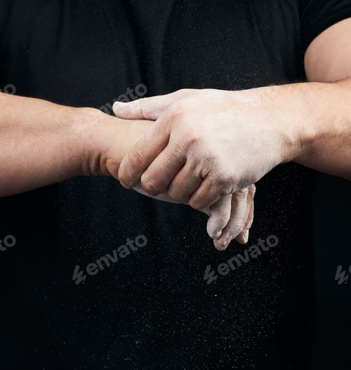 Preview: Muscular Athlete In A Black Uniform Rubs His Hands With White Dry Sports Magnesia, Powder Scatters