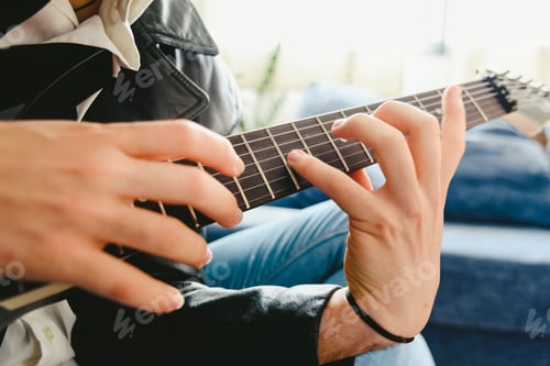 Preview: Young Man Practicing With His Electric Guitar On The Sofa Of His House Learning.
