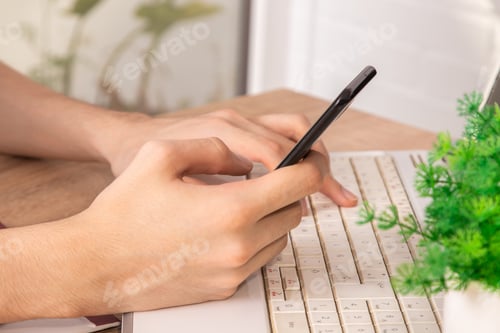 Preview: Closeup Top View Of Hands With Mobile Phone And Computer On Desk