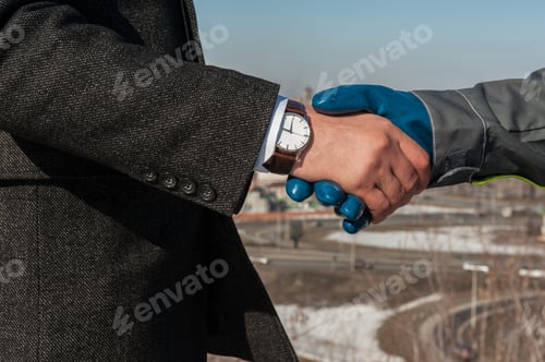 Preview: Industry Worker With Glove Shakes Hands With Businessman