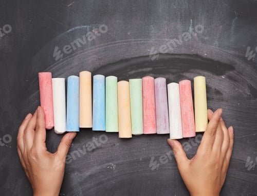 Preview: Multicolored Chalk On A Black Background And Two Female Hands, Top View