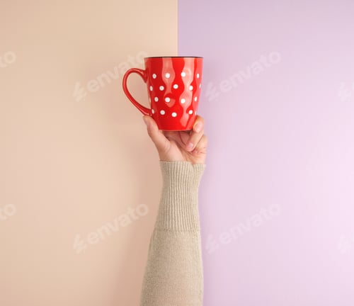 Preview: Female Hand Holding A Red Ceramic Mug With White Polka Dots, Abstract Background