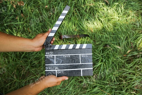 Preview: Man Is Holding In Hands Black Clapperboard With Film Lying On The Grass Outdoors. Directing And Of