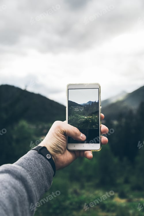 Preview: Man Taking Picture Of The Mountains On His Phone In Cloudy Weather