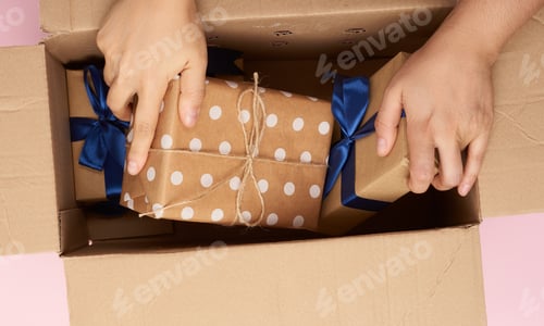 Preview: Female Hand Takes Out Wrapped Gifts From A Cardboard Box, Top View