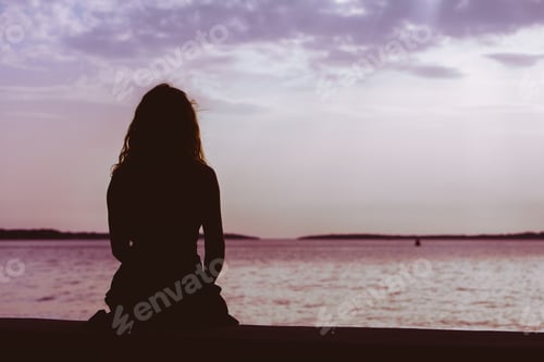 Preview: Woman Silhouette Sitting On The Beach Looking At Sunset Over The Sea. Copy Space