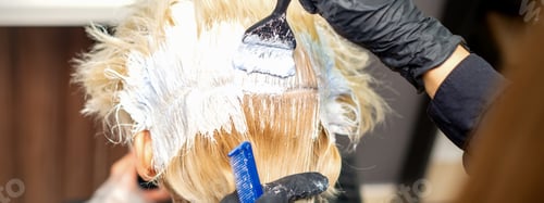 Preview: Back View Of Hands Of Hair Stylist Dyeing Hair Of Young Woman In White Color In Hair Salon
