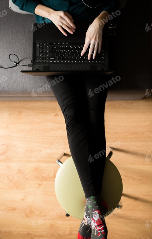 Preview: Girl In Dark Green Blouse Is Sitting On Grey Couch At Home. Working Day Of Freelancer Earning Money