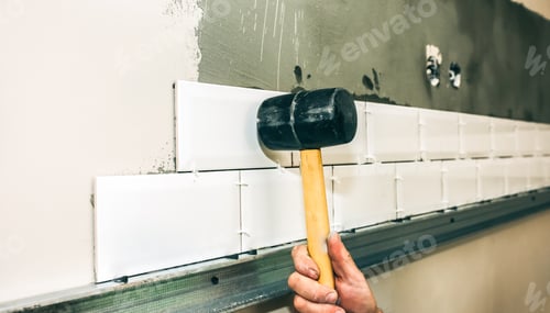 Preview: Man Is Putting White Tiles On The Grey Concrete With A Help Of Hammer. Maintenance Repair Works