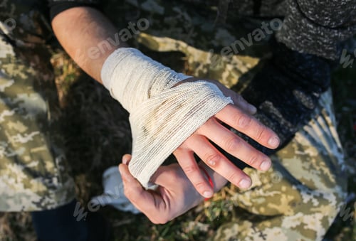 Preview: Man Is Putting Bandage On Sprained Wrist. Twisted Arm. Injured Tourist In The Nature. Hiking.
