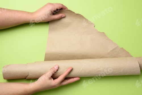 Preview: Two Female Hands Hold Rolled Brown Paper, Green Background, Top View