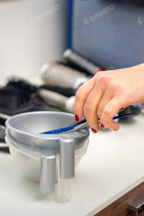 Preview: Hand Of Hairstylist Prepares Dye In Bowl For Coloring Hair In Hairdress Salon
