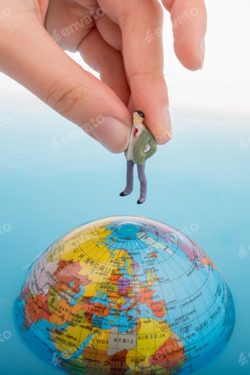 Preview: Hand Holding A Little Figurine On The Top Of The Globe In Water
