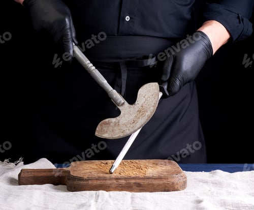 Preview: Male Cook In Black Uniform And Black Latex Gloves Holds A Large Sharp Vintage Knife For Meat And