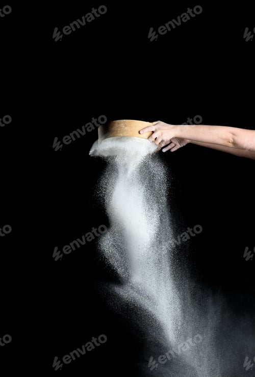 Preview: Female Hand Sifts White Wheat Flour Through A Round Wooden Sieve On A Black Background, Product Is