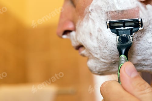Preview: Man Shaving His Face With The Razor Blade Through Shave Foam. Men Skin Care Concept.
