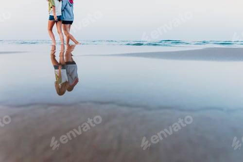 Preview: Two Girls Walk Along The Shore Of The Beach At Sunset.
