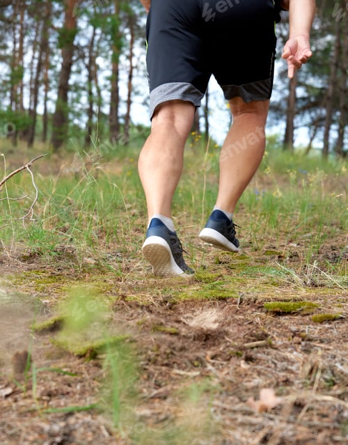 Preview: Adult Man In Black Shorts Runs In The Coniferous Forest, Concept Of A Healthy Lifestyle And Running