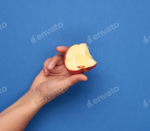 Preview: Female Hand Holding A Bitten Red Apple On A Blue Background, Close Up