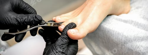 Preview: Closeup Of A Pedicure Master Is Cutting And Removing Cuticle With Nail Tongs On Female Toes In A