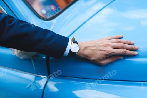 Preview: Man Holding Hand With Watch On Old Blue Car