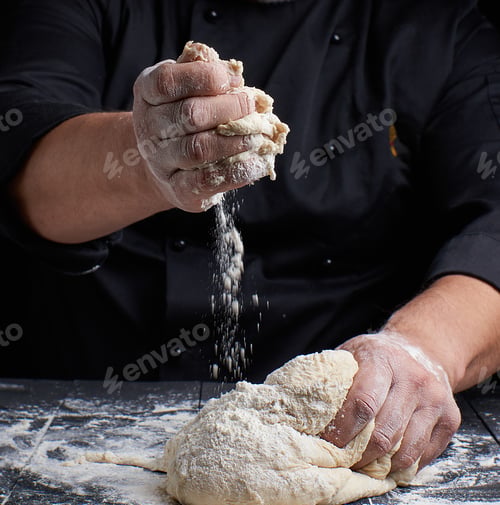 Preview: Men'S Hands Knead White Wheat Flour Yeast Dough On A Black Wooden Table
