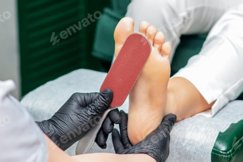 Preview: Pedicurist Cleans Foot With Special Grater For Scrubbing Heels Close Up.