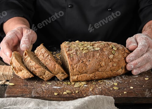 Preview: Sliced Rye Bread With Pumpkin Seeds On A Brown Wooden Board, Close Up