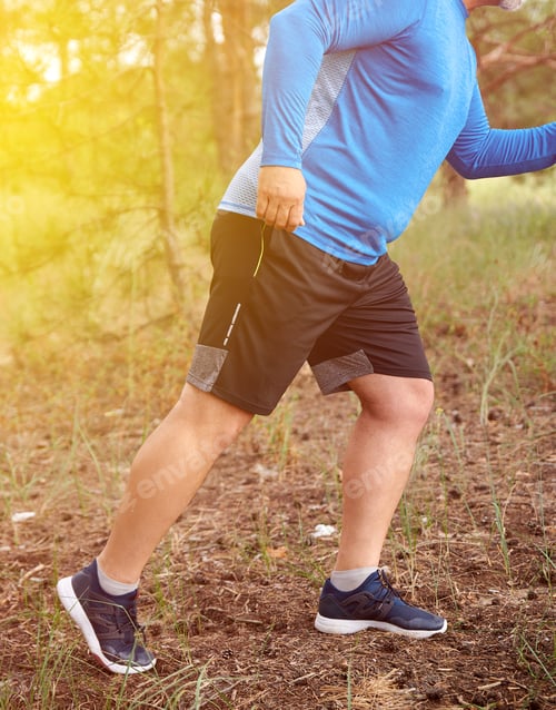 Preview: Adult Plump Athlete In Blue Uniform, Sneakers And Black Shorts Runs Through The Middle Of The Woods