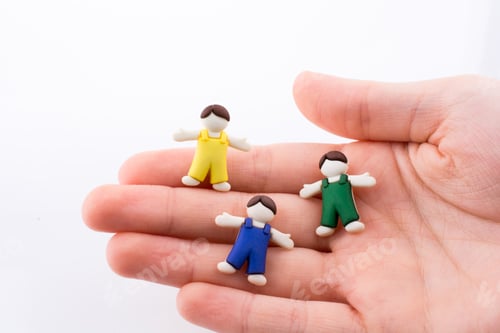 Preview: Hand Holding Colorful Dressed Children Figures On A White Background