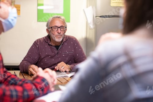 Preview: A Healthy Senior Man Living With Hiv Working In A Casual Office With Colleagues