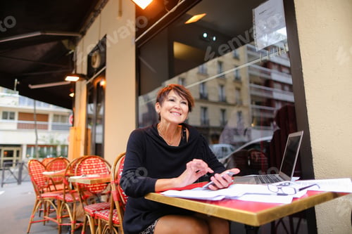 Preview: Middle Aged Female Student Using Laptop For Writing A Research Work. Woman Sitting At Red Table In