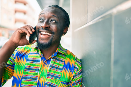 Preview: Young African American Man Talking On The Smartphone Leaning On The Wall At Street Of City.