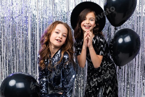 Preview: Black Friday. Two Cute Stylish Young Girls In Holiday Dresses With Black Balloons On A Shiny