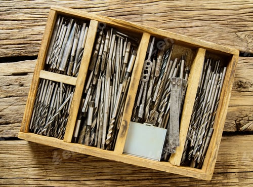 Preview: Working Tools. A Box With Drills On A Wooden Background.