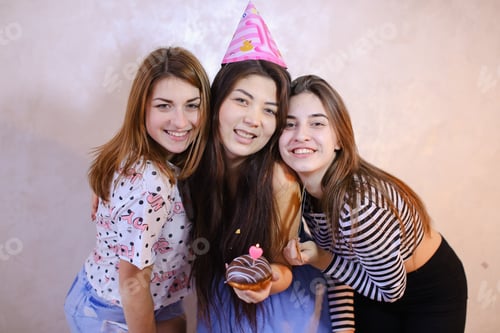 Visualização: Amigas alegres e bonitas riem e sorriem, duas garotas parabenizam a morena no aniversário