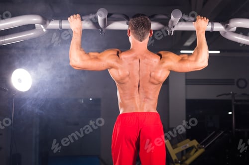 Preview: Strong Young Man Doing Pull Up Exercise On Horizontal Bar In Gym