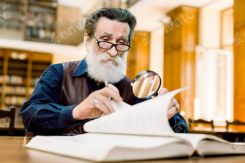 Preview: Focused Elderly Stylish Man Teacher, University Professor, In Eyeglasses Sitting In Old Library And