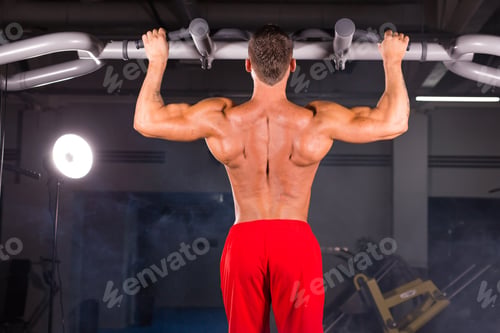 Preview: Strong Young Man Doing Pull Up Exercise On Horizontal Bar In Gym