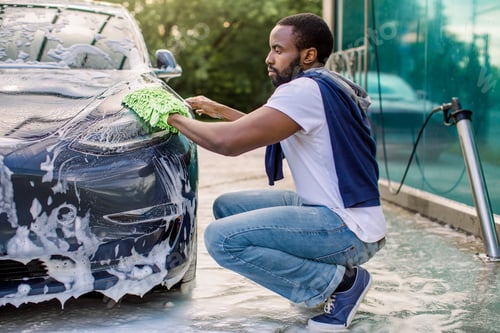 Preview: Side View Of Young Handsome Bearded African Man In T-Shirt And Jeans Cleaning His Luxury Electric