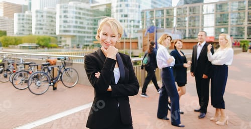 Preview: Close Up Face Blonde Secretary Looking At Camera And Smiling With Blue Case In And Talking Partners