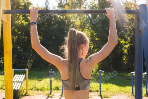 Preview: Young Athletic Fitness Woman Working Out At Outdoor Gym Doing Pull Ups At Sunrise.
