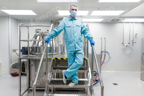 Preview: Caucasian Scientist In Blue Lab Suit And Gloves Stand On Steel Ladder Hold Hands On Handrails, Look