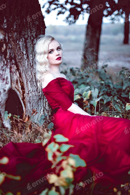 Preview: Fashion Gorgeous Young Blonde Woman In Beautiful Red Dress In A Fairy-Tale Forest. Magic Atmosphere