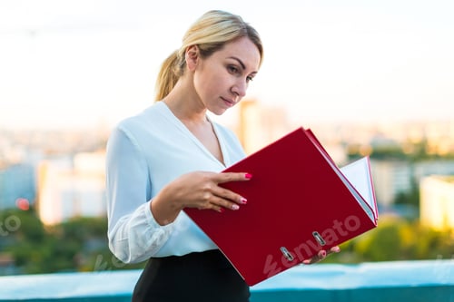 Preview: Young Attractive Serious Blonde Caucasian Business Lady Stand On The Roof With Red Paper Folder In
