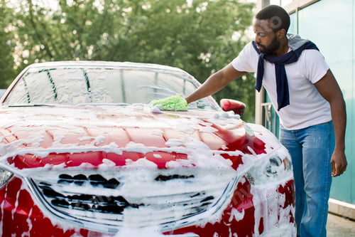 Preview: Young Attractive African American Man Washing His Red Luxury Car In A Self-Service Car Wash Station