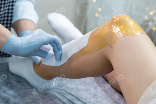 Preview: Bodycare Concepts. Close-Up Of Beautician During Wax Depilation Procedure Of Woman Legs By Wax